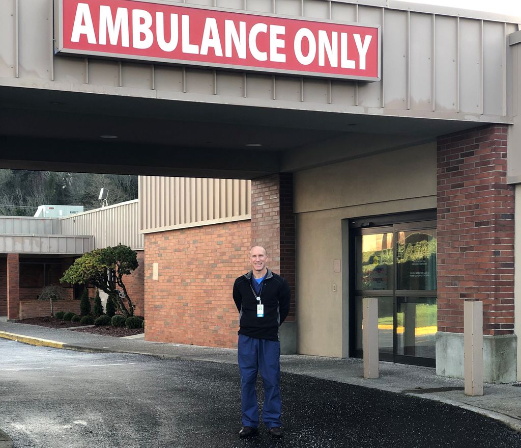 man standing in front of a hospital emergency room