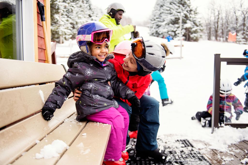 mom and daughter, wearing ski helmet and snowsuits
