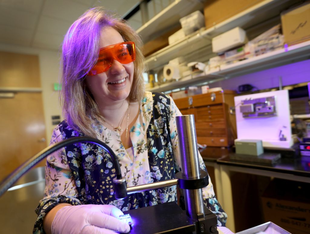 Carmem Pfeifer, lit up by a machine that cures dental materials