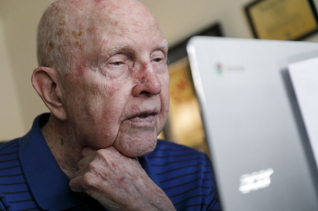 man with hand on chin, talking with someone via video chat