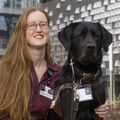 woman with her arm around a large black lab dog