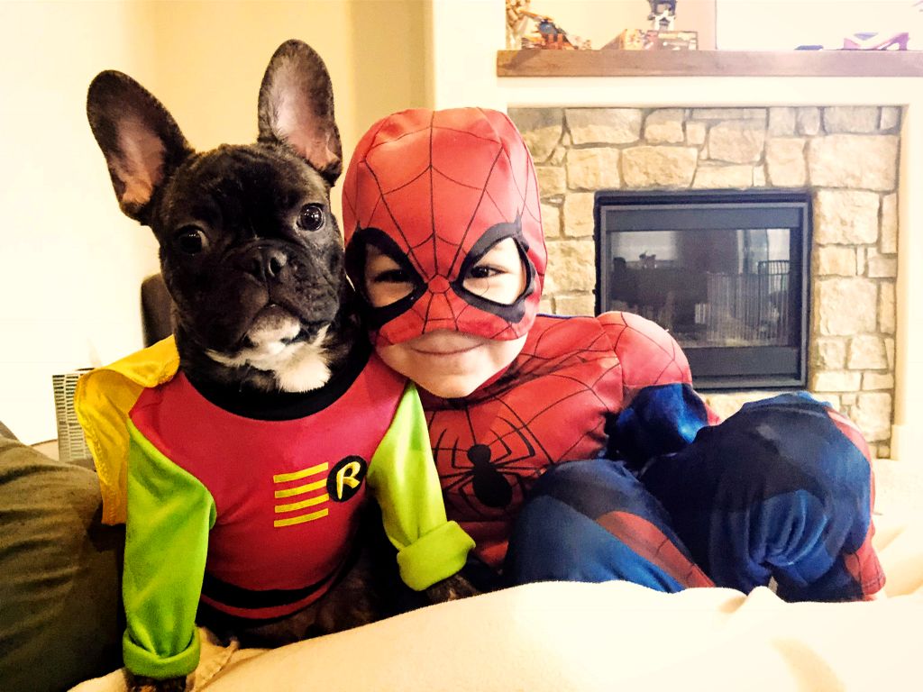 boy dressed as spider man, hugging his dog