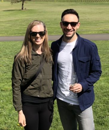 woman and man, standing with arms around one another in a grape vineyard