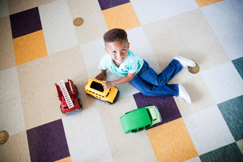 overhead view of a child playing on the floor with some trucks