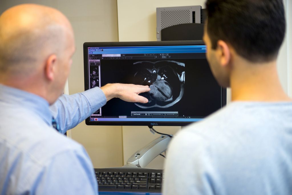 dr broberg, left, with another man, seen from behind, as they look at an image of a heart on a screen