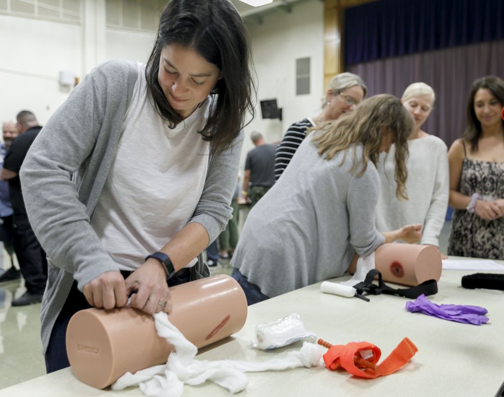 woman, hunched over a plastic leg, and learning to pack gauze into a wound