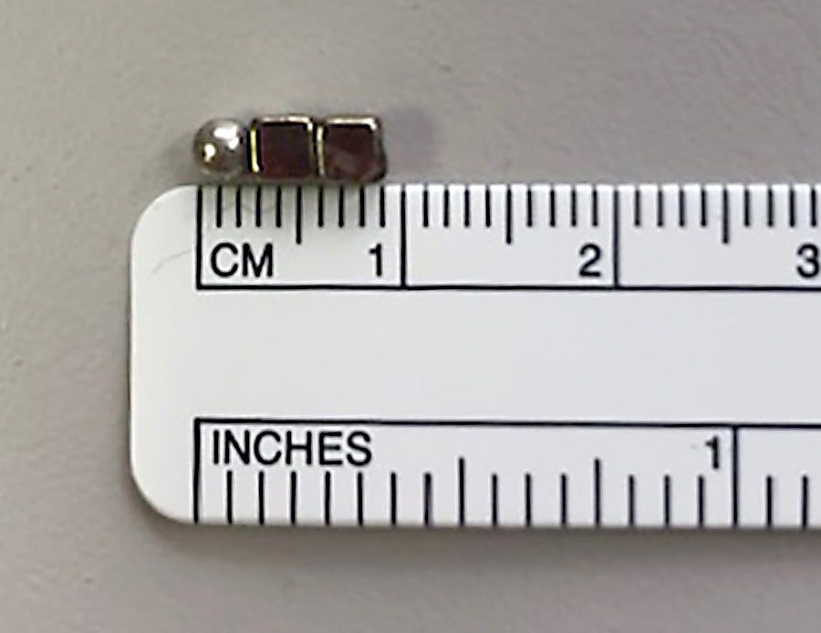 three tiny toy magnets lined up against a ruler