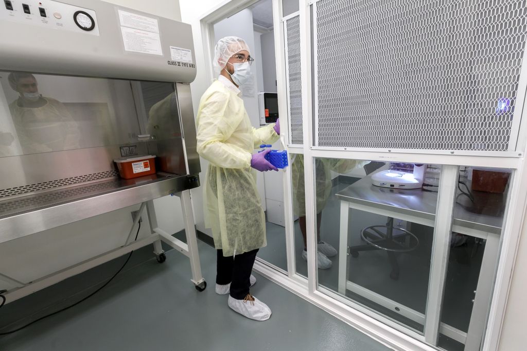 Man in full protection gear, entering into a room through a heavily screened door
