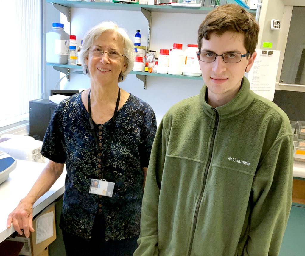 woman on left, in scrubs, and brendan, on right, standing side by side and both looking into camera