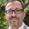 Matthias Merkel, M.D., Ph.D. A person with black framed glasses and facial hair, smiling.