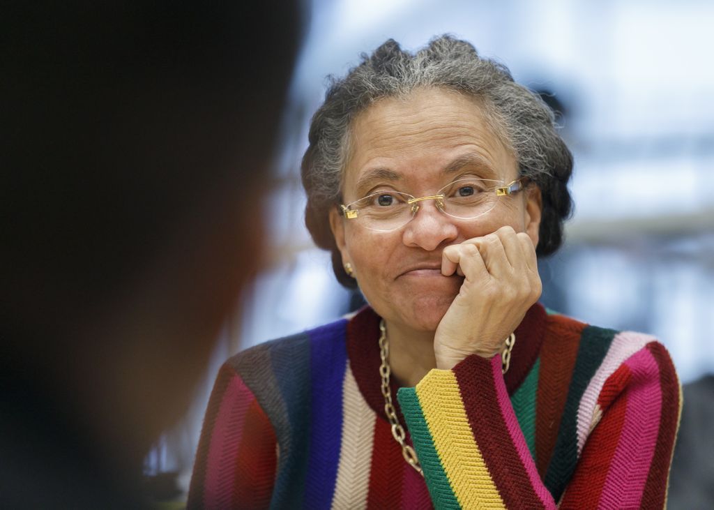 woman sitting with hand on chin, smiling as she listens attentively