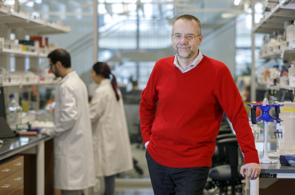 beer standing in a research lab with people working behind him