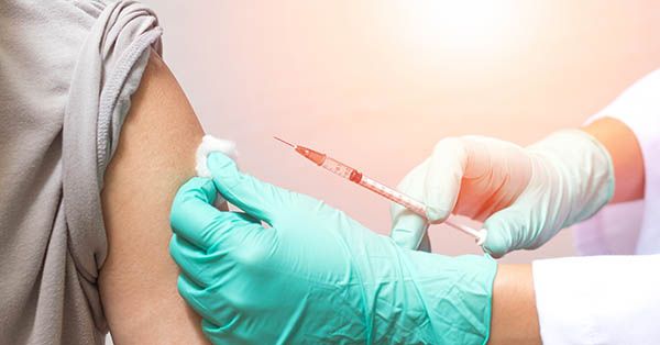 Vaccination healthcare concept. Hands of doctor or nurse in medical gloves injecting a shot of vaccine to a man patient