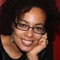 close-in headshot of Raina Croff, Ph.D., a smiling Black woman in glasses resting her chin on her left hand.
