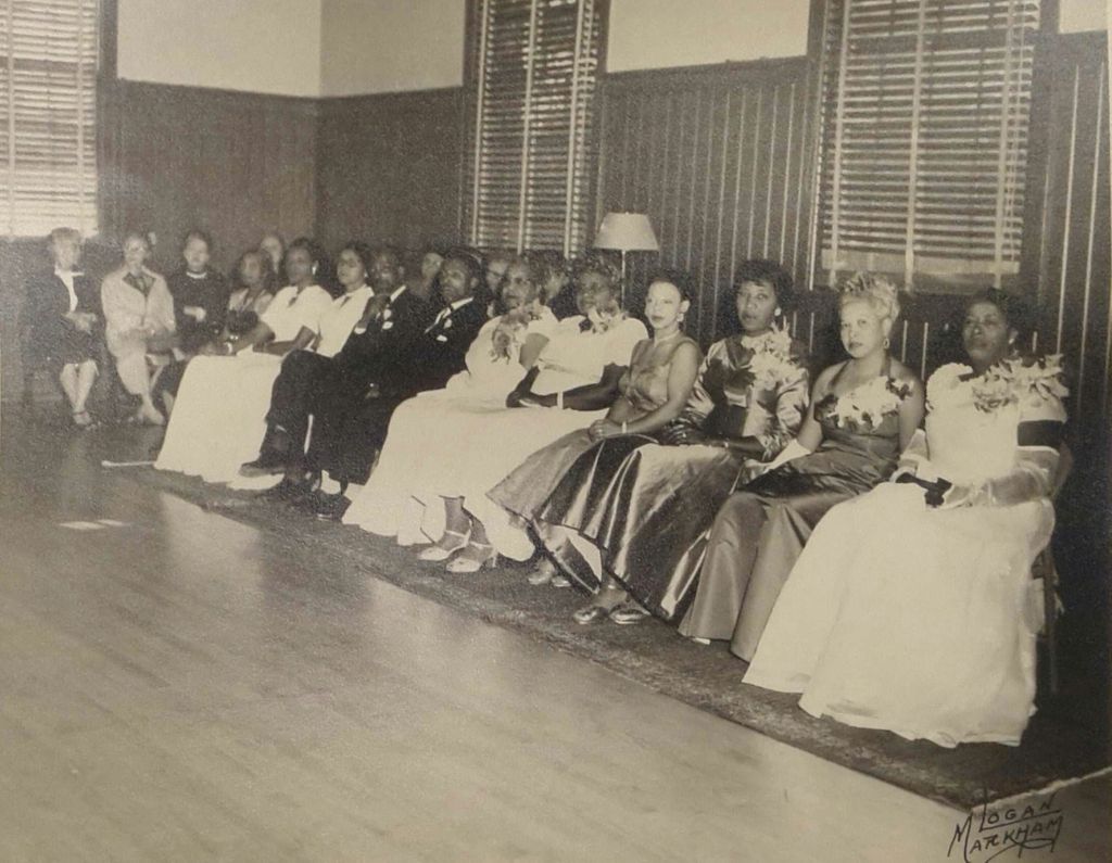 Black and white photo of a Billy Webb Elks Lodge dance, showing a row of seated men and women in formalwear at the edge of a wooden dance floor.