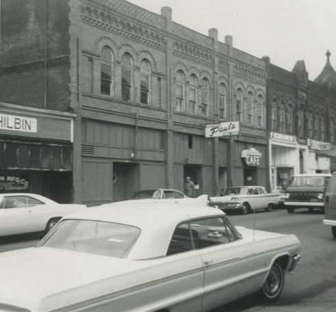 Black and white exterior shot of the entrance to Paul's Paradise Night Club in Portland, OR; a white car is in the foreground.