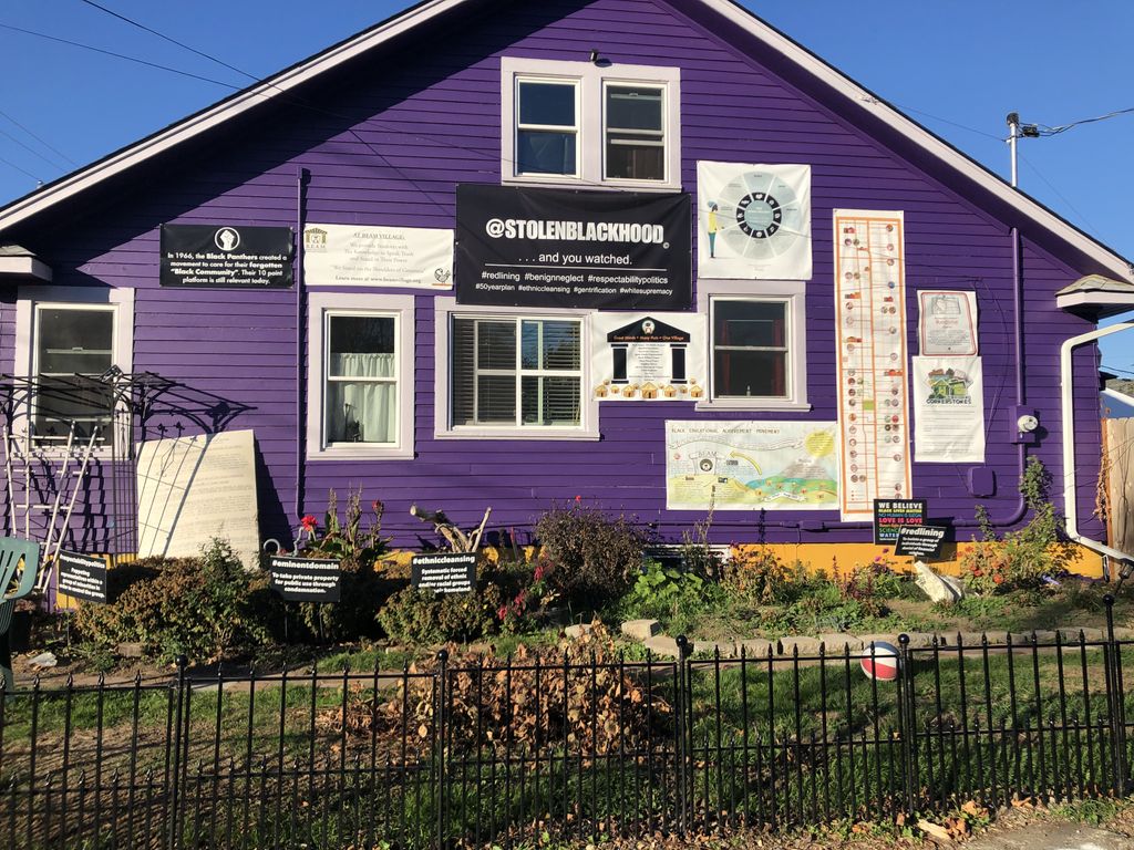 BEAM (Black Educational Achievement Movement)'s homebase in a purple residential home in Portland, OR; there are multiple posters and signs affixed to the outside of the building with messages about community values and stolen blackhood