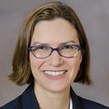 Alison Edelman, a person with short brown hair, wearing glasses, smiling.