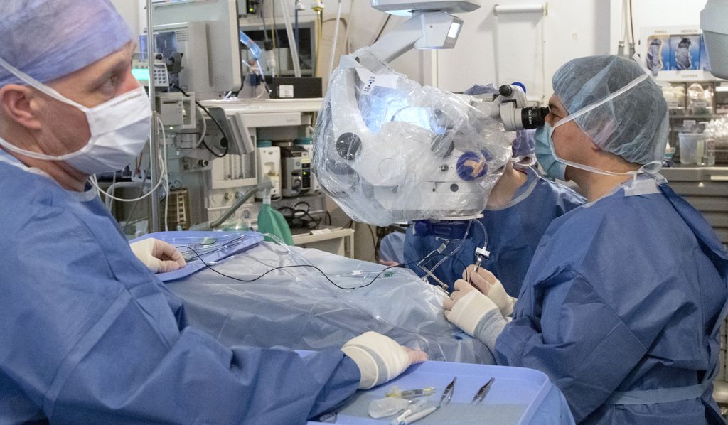 doctors drawing up solution from a syringe in a surgery suite