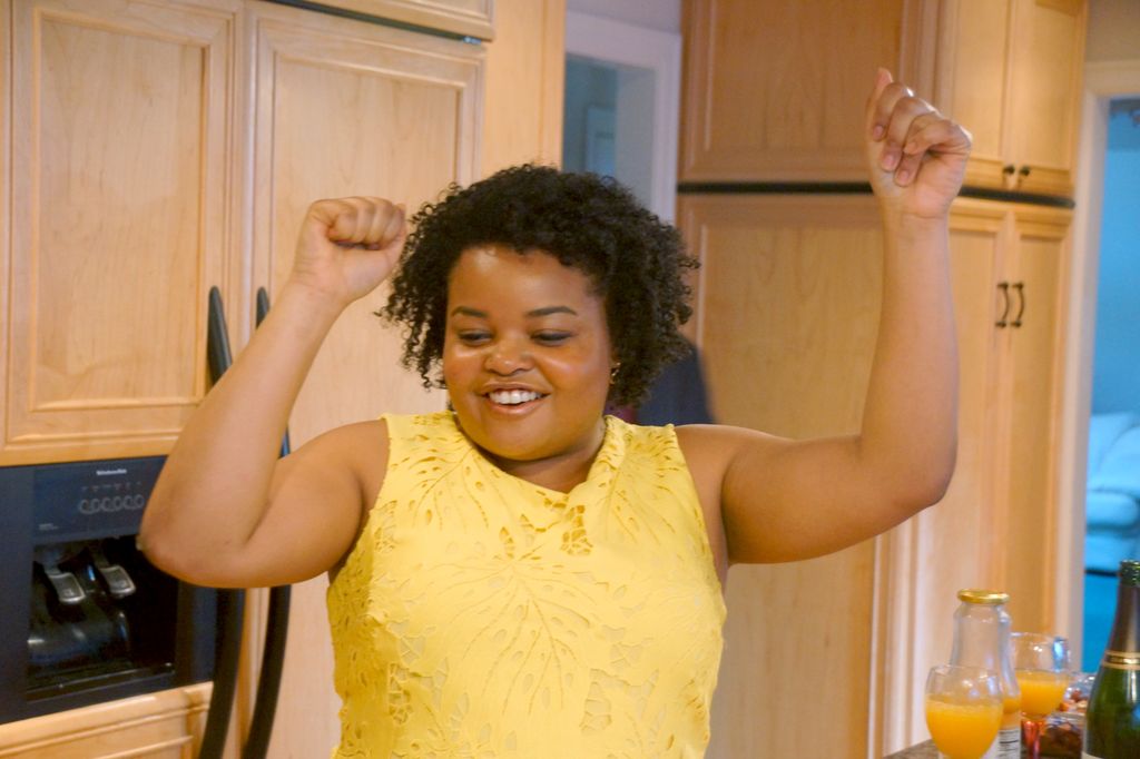 woman in yellow dress, dancing with hands above her head in fists