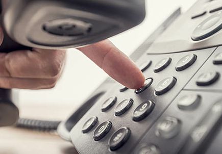 Closeup of male hand holding telephone receiver while dialing a