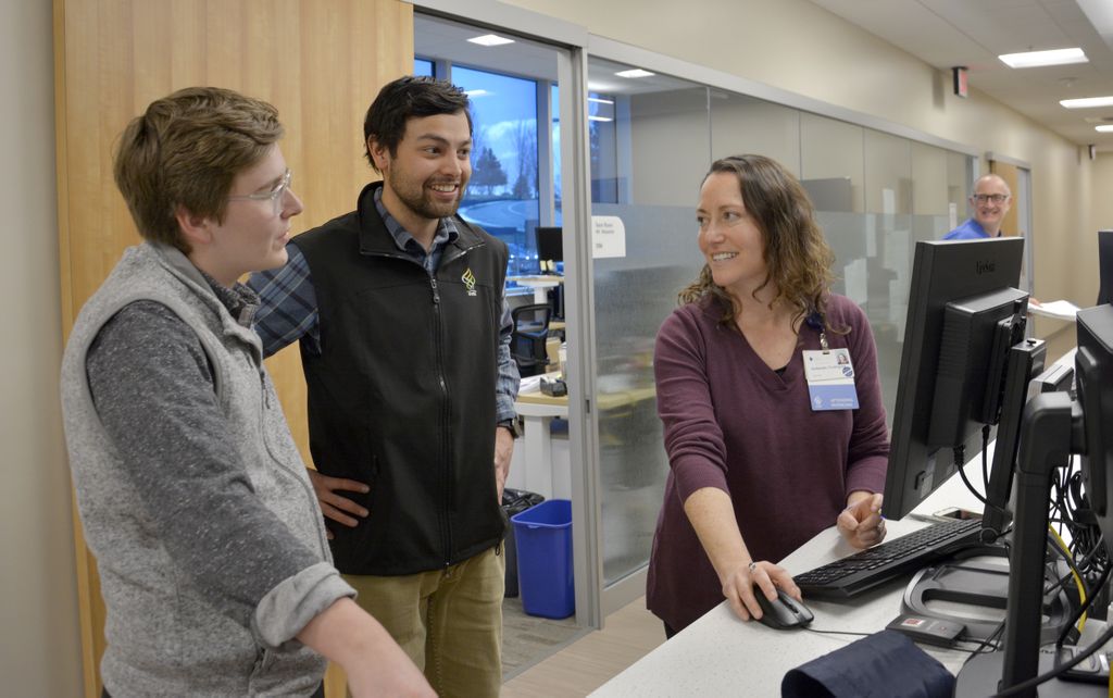 three people, gathered around a computer