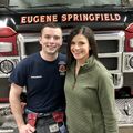 EMt and young woman standing in front of fire truck