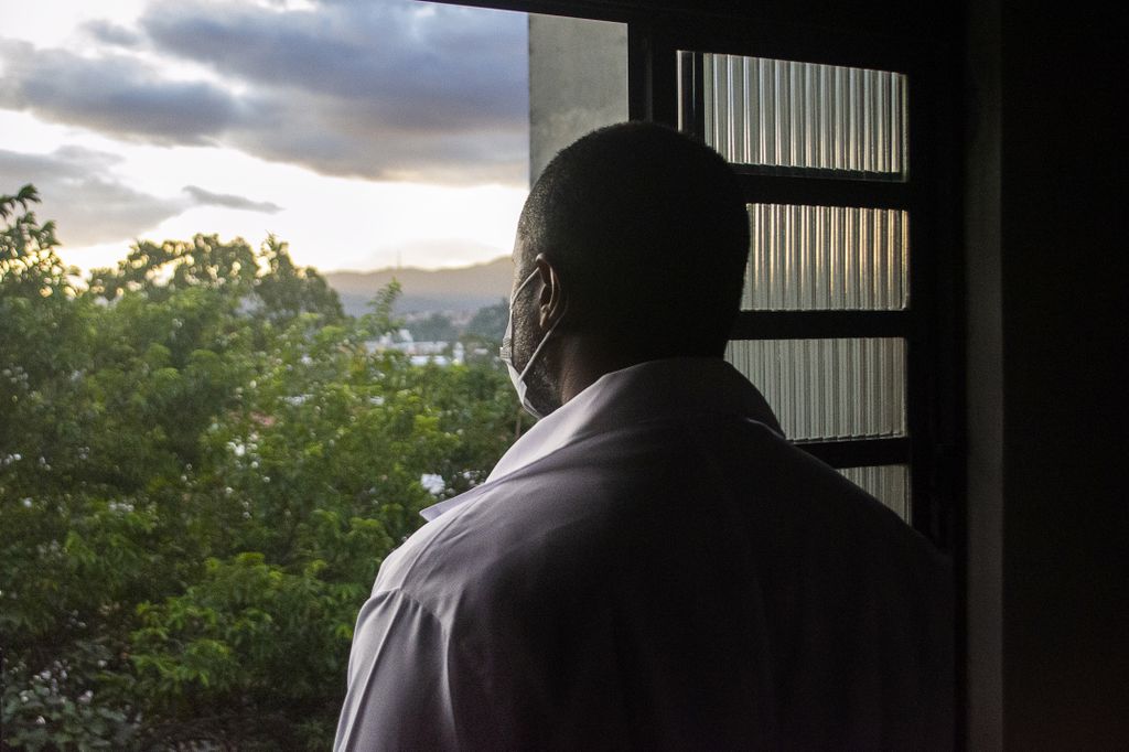 african american man with face mask looking out window