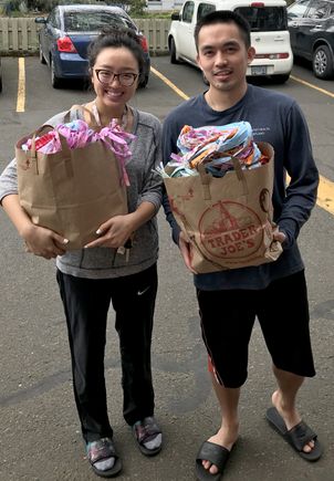 a pair of young people, woman and man, holding shopping bags full of masks