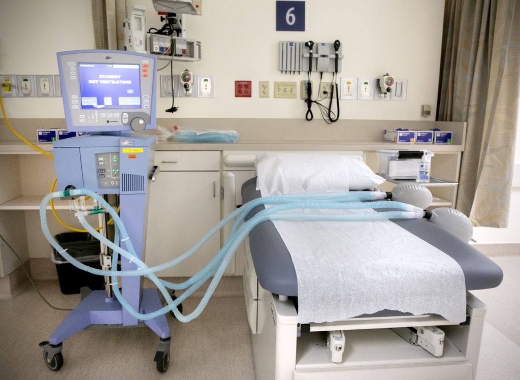 a hospital bed with a ventilator machine next to it, that has two attachments, instead of one