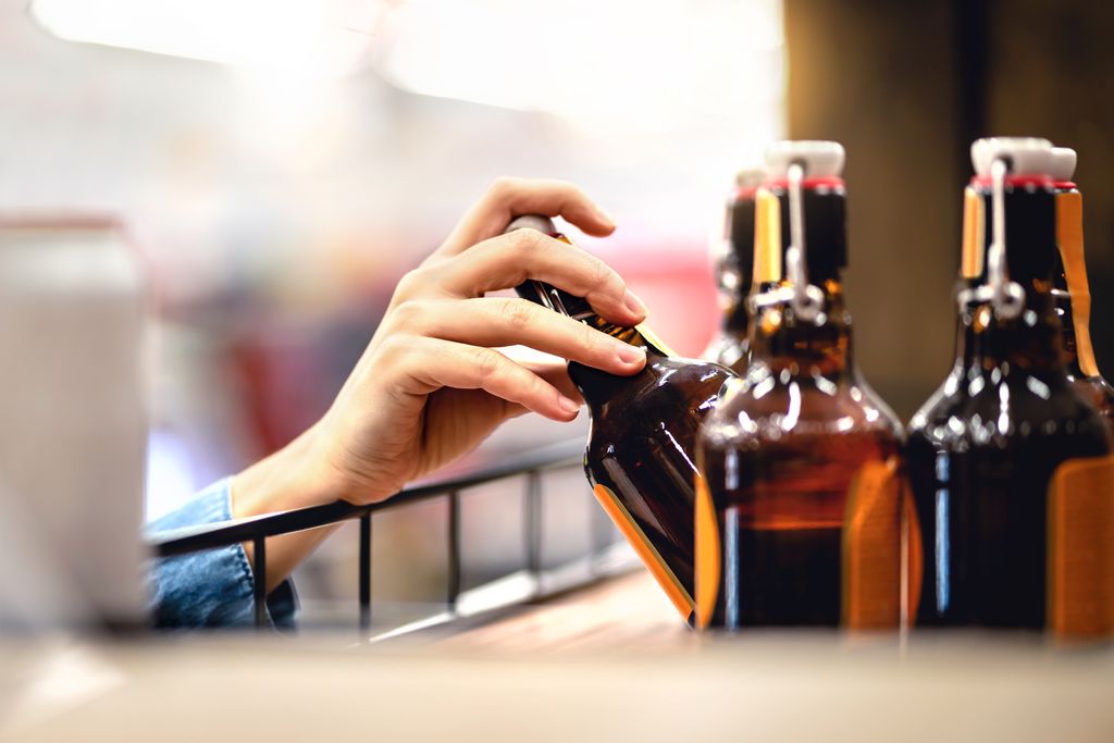 woman's hand reaching into shelf to take a bottle of beer