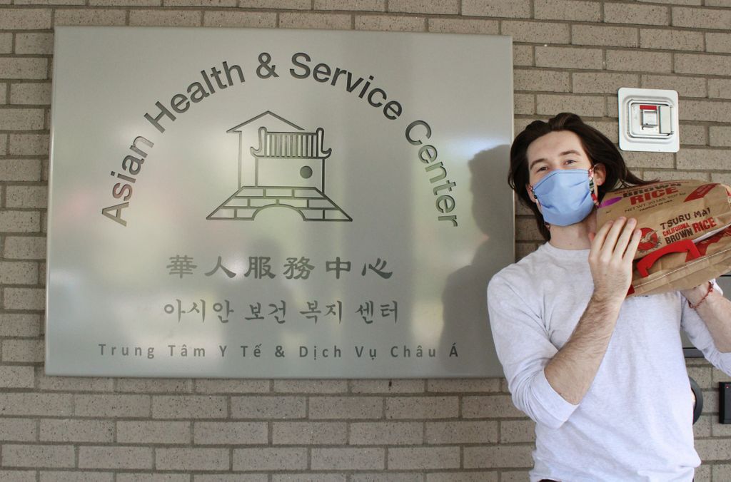 person holding a bag of rice on shoulder near a sign for the Asian health and service center