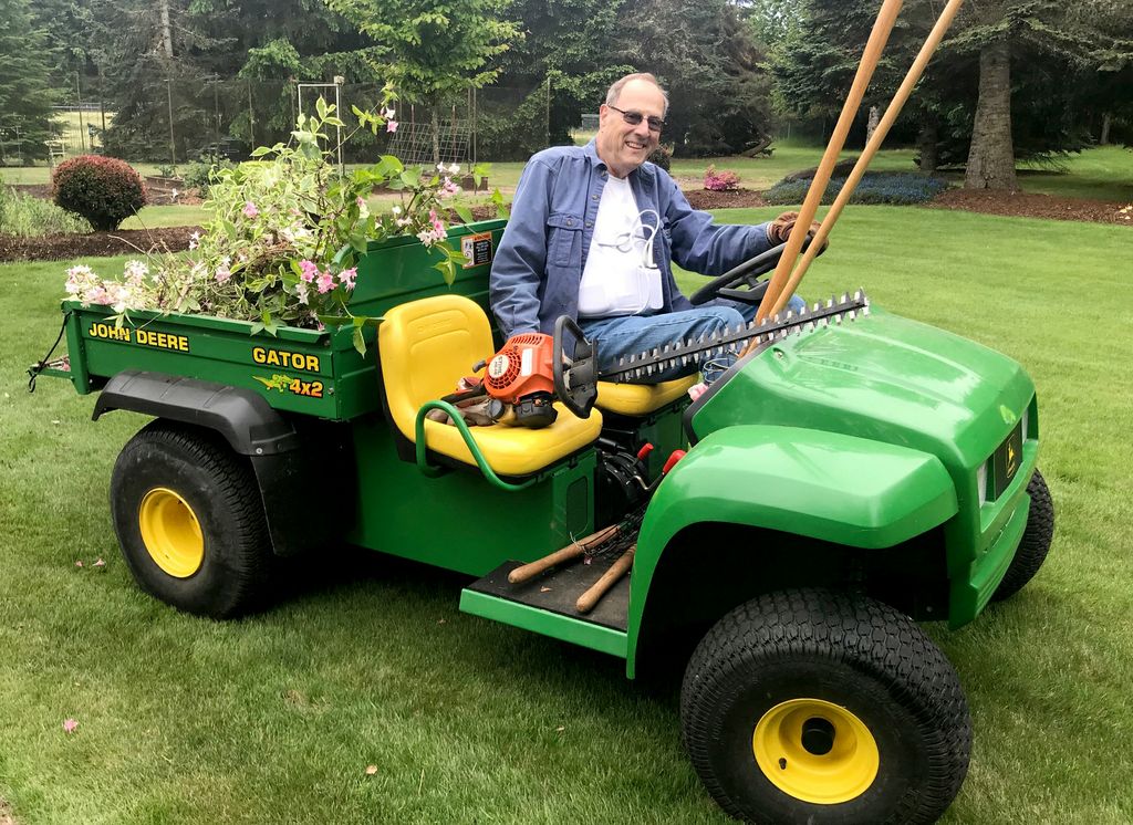 man on a fourwheel work gator, with chainsaw, working in garden