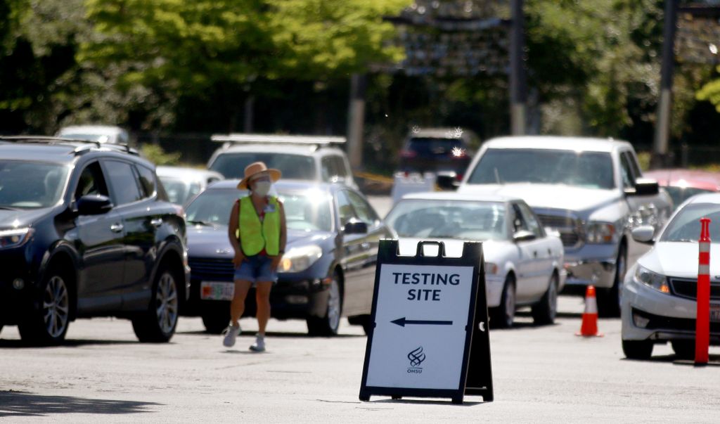 EXPO drive-up COVID-19 testing: a sign board sits in a parking lot near a line of cars