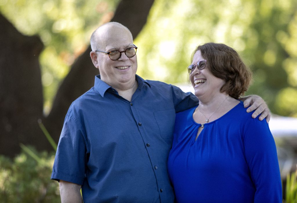 man smiling and hugging his wife, as she looks at him adoringly