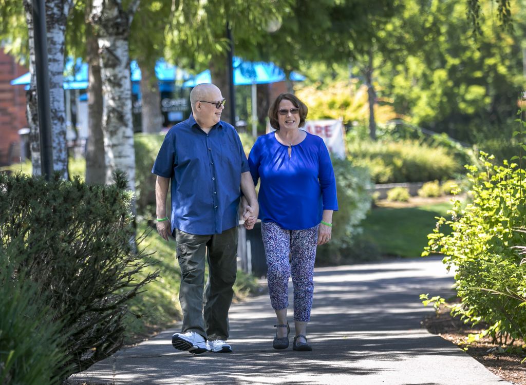 Man and woman holding hands, walking on a wooded path