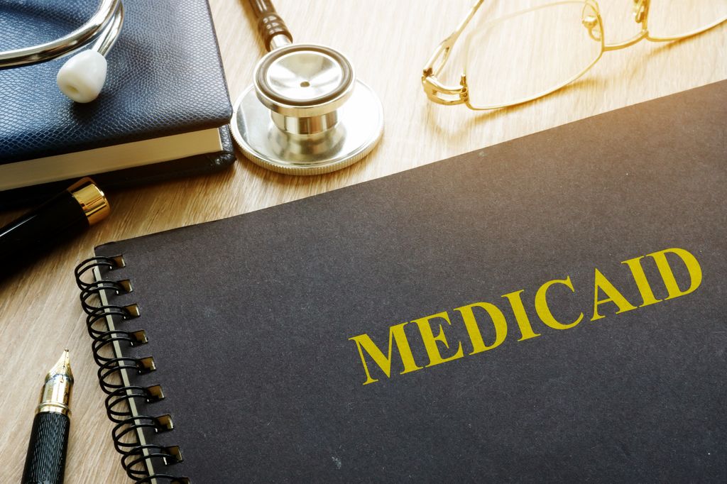 book with MEdicaid written across front, stethoscope and pencil lying nearby