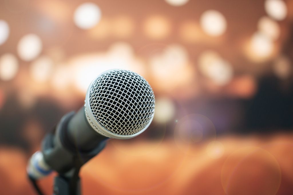 close up microphone, with  the background of a speaking auditorium that is out of  focus