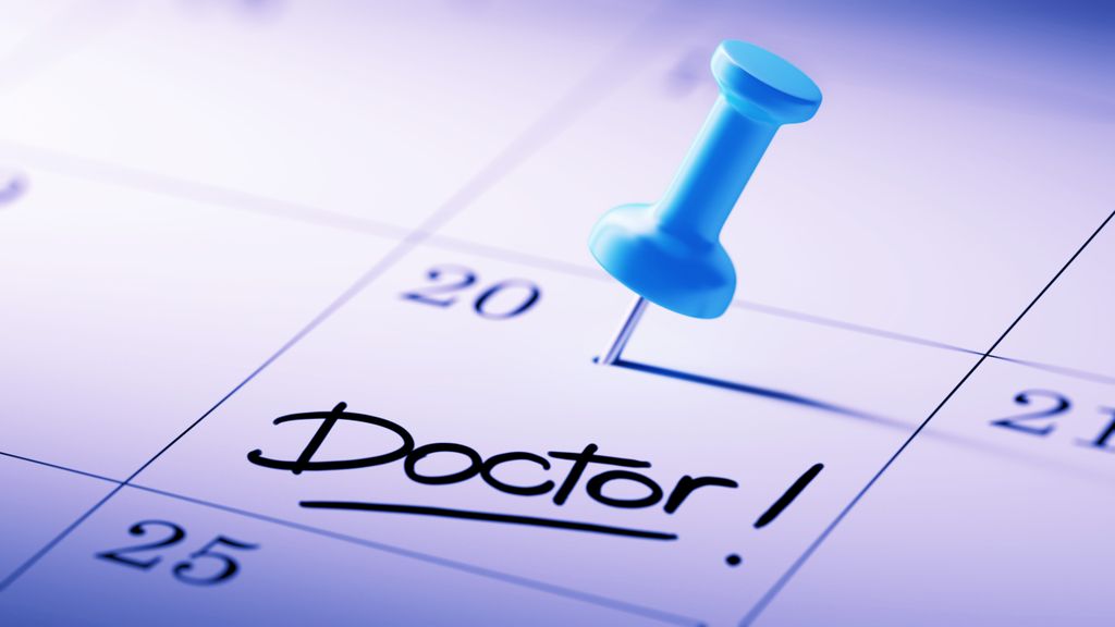 close up of a calendar with the word, doctor, written on it, and a thumbtack marking the spot