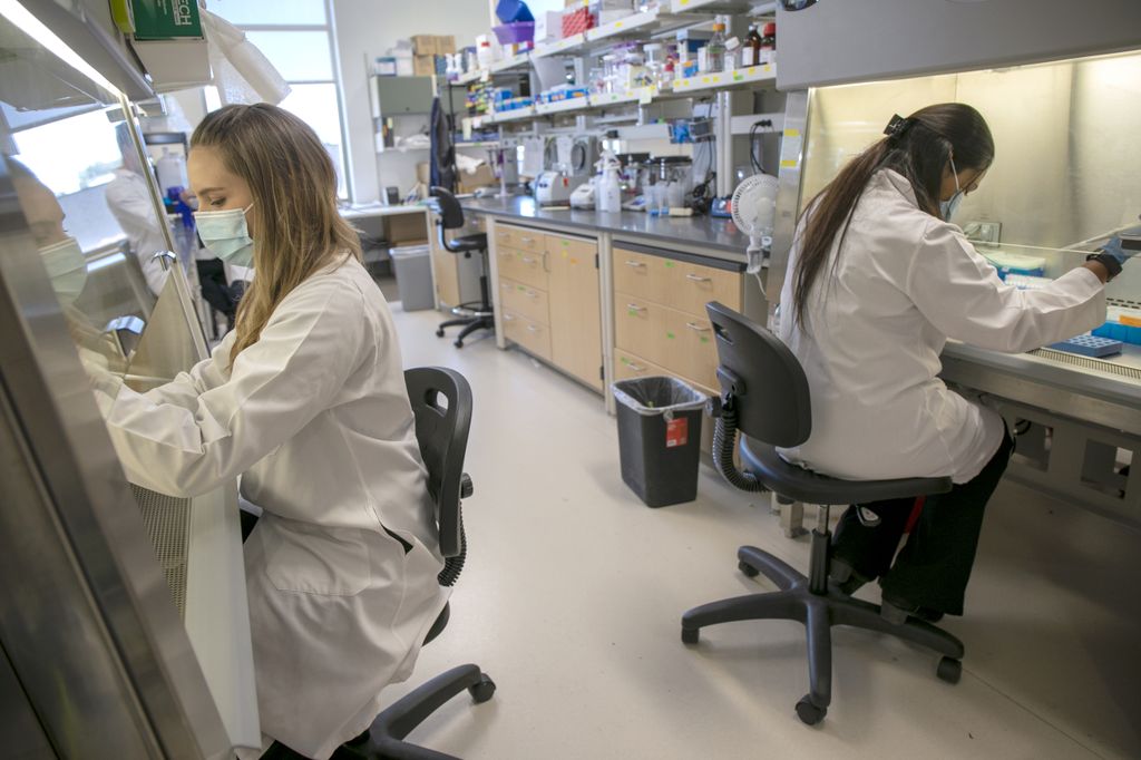 Lauren Rust, Ph.D. (left) and Sreya Biswas, Ph.D. (right) shown working in lab coats in Ben Burwitz's medical laboratory.