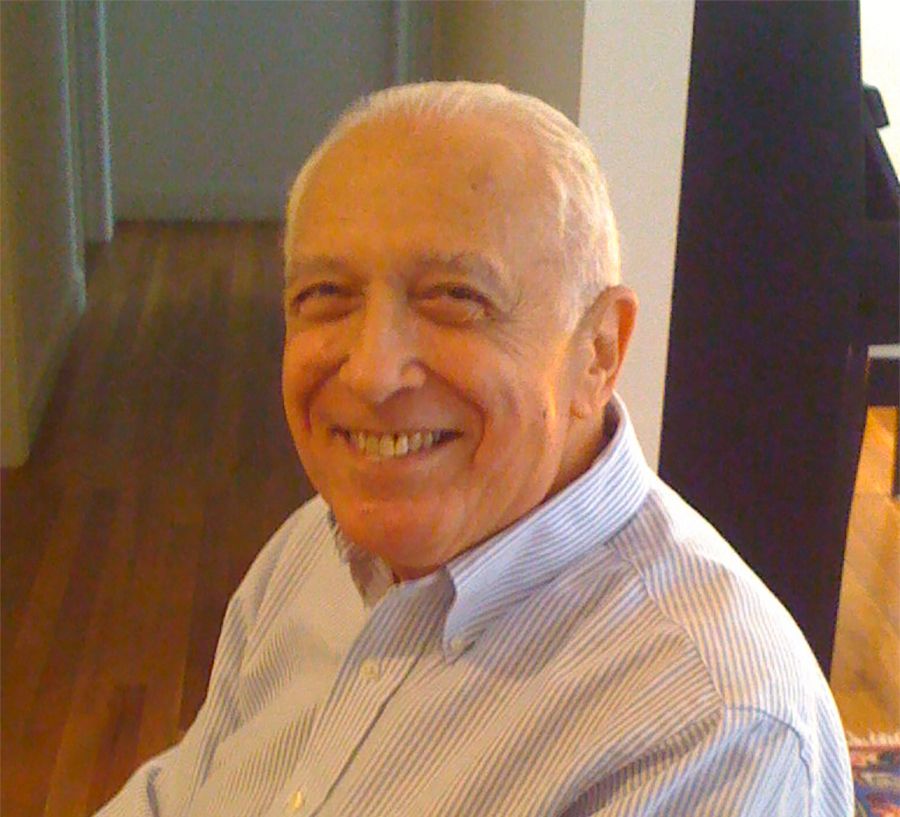 Color photo of Leonard Laster, a smiling, white-haired Caucasian man in a tan sweater.