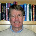 Headshot of Martin Kelly, Ph.D., a smiling white man in a sweater, posing in front of a bookshelf.