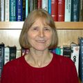 Headshot of Oline Ronnekleiv, Ph.D., a smiling white woman in a red sweater, posing in front of a bookshelf.