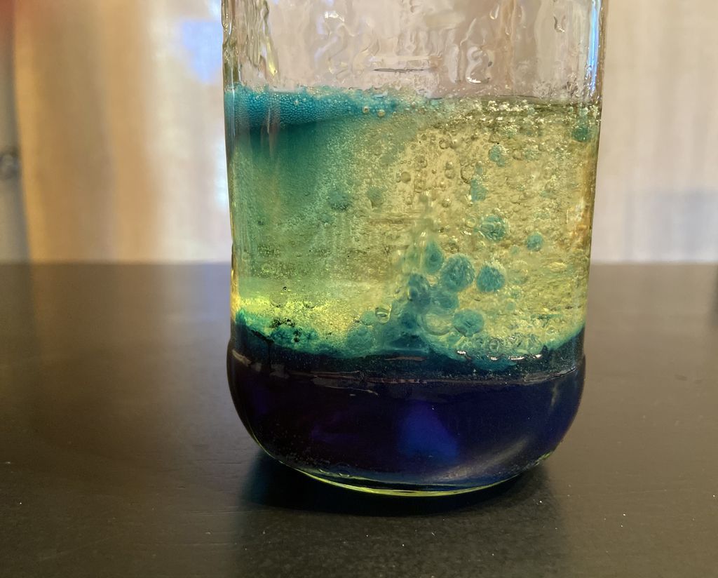 Closeup shot of a homemade "lava lamp" toy: blue oil and water in a plastic bottle.