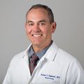 headshot of Kalani Raphael, a smiling, balding Hawaiian male in a white lab coat