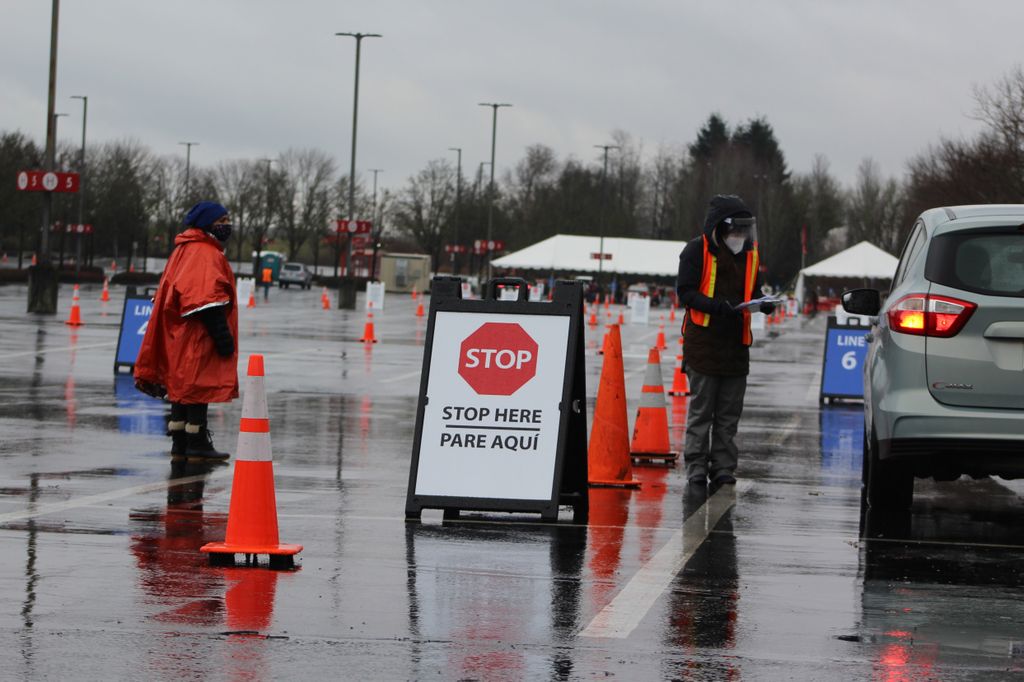 Two people direct vehicle traffic in a parking lot.