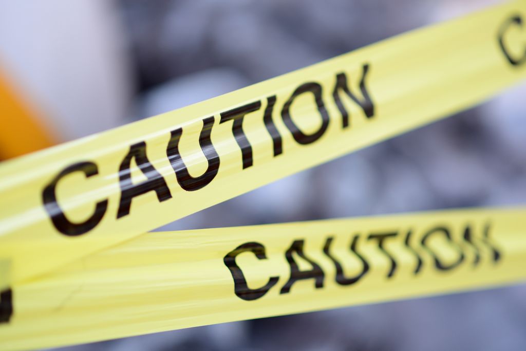 two pieces of yellow 'caution' tape are in focus in the foreground; background is blurred.
