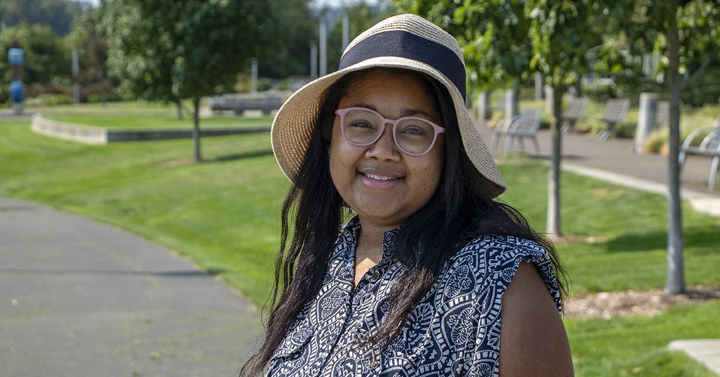 Heart transplant patient Vanessa Trotter smiles on a sunny day, wearing a floral dress, sunhat, and eye glasses.