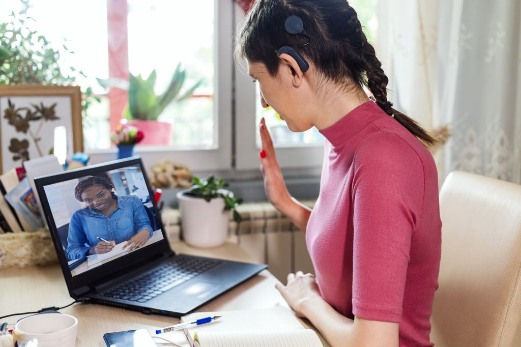 Deaf and hard-of-hearing scientists call for equity, inclusion. Young woman with cochlear implant studying online at home. She using modern technology.