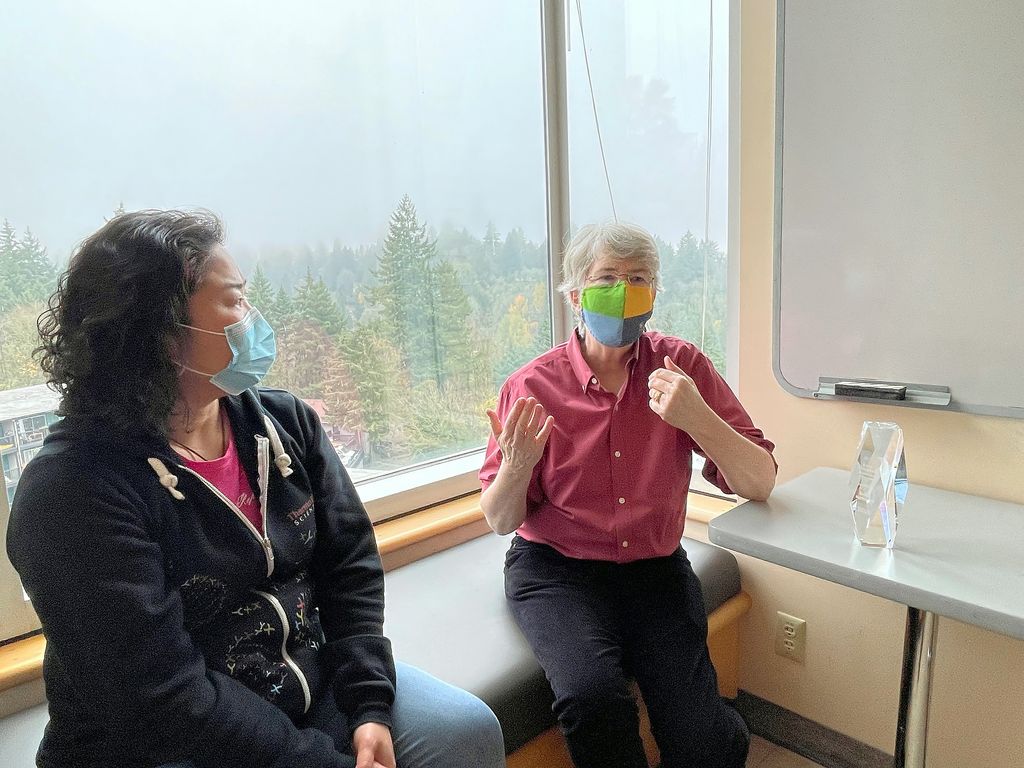Susan Hayflick (right) a woman with short hair, glasses and mask next to her award.